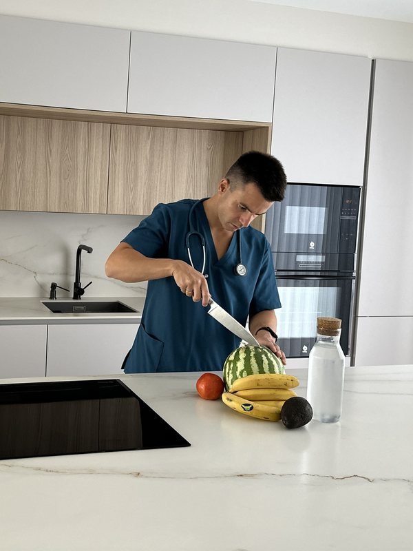 Pablo Berna en la cocina, con un cuchillo y fruta en la encimera